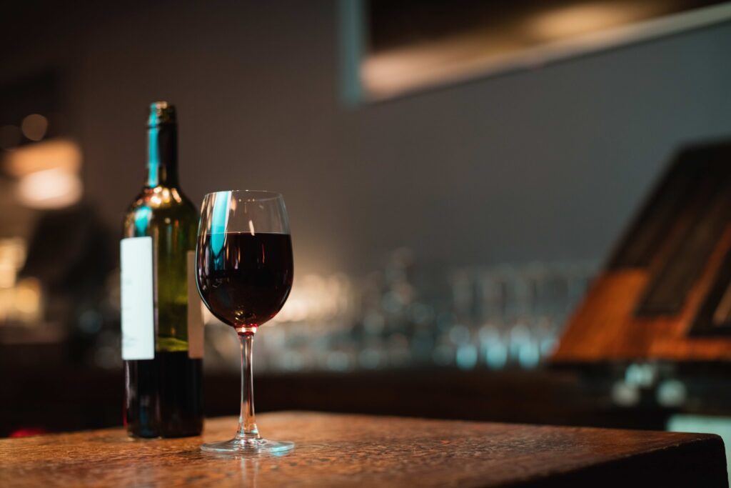 外科陳榮堅醫師-Glass of red wine and bottle on bar counter at bar